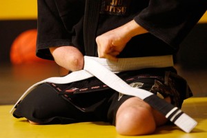 Joey Bozik ties his belt as he prepares for a Brazilian jiu-jitsu training sesson.